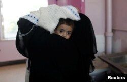 A woman carries a child at the malnutrition ward of al-Sabeen hospital in Sanaa, Yemen Sept.11, 2018.