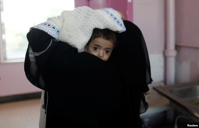 A woman carries a child at the malnutrition ward of al-Sabeen hospital in Sanaa, Yemen Sept.11, 2018.