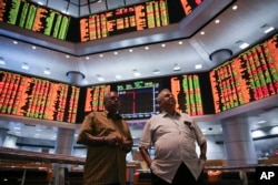 Two men watch trading boards at a private stock market gallery in Kuala Lumpur, Malaysia, Aug. 25, 2015.