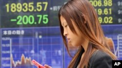 A woman walks by an electronic stock board of a securities firm in Tokyo, Aug. 31, 2015.