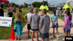 Representative Samba Baldeh, in bright green at center, greets young runners in a fundraiser for nonprofit Strides for Africa, an event during Africa Fest 2021 in Madison, Wis. Aug. 21, 2021. (Carol Guensburg/VOA)