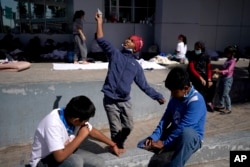 A migrant boy, center, launches a paper airplane while playing with other migrant kids at a plaza near the McAllen-Hidalgo International Bridge point of entry into the U.S., after being caught trying to sneak into the U.S. and deported, Thursday, March 18