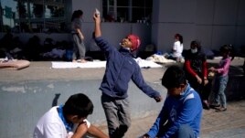 A migrant boy, center, launches a paper airplane while playing with other migrant kids at a plaza near the McAllen-Hidalgo International Bridge point of entry into the U.S., after being caught trying to sneak into the U.S. and deported, Thursday, March 18