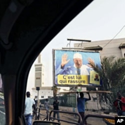 A defaced poster of Senegal's President Abdoulaye Wade (R) with paint splattered on it, is seen through the window of a taxi driving through the center of Dakar, March 1, 2012