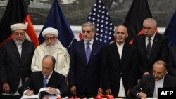 阿富汗國家安全顧問哈尼夫•阿特馬爾（右）和美國駐阿富汗大使詹姆斯•坎寧安（左）在阿富汗總統府簽署安全協議。阿富汗總統阿什拉夫•加尼（右二）和阿富汗的新的行政長官阿卜杜拉（中）出席簽字儀式。