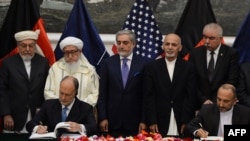 Cố vấn An ninh Quốc gia Afghanistan Hanif Atmar (phải) và Đại sứ Mỹ tại Afghanistan James Cunningham (trái) ký hiệp định an ninh song phương tại Dinh Tổng thống ở Kabul, ngày 30/9/2014.