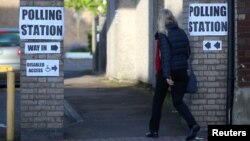 A woman enters a polling station as voting begins in local government elections in London, May 3, 2018. 