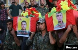 FILE - Members of the Kurdish People's Protection Units (YPG) carry coffins of their fellow fighters, who were killed during clashes with Islamic State fighters on the Iraqi-Syrian border, during their funeral in Ras al-Ain city, in Syria's Hasakah provin