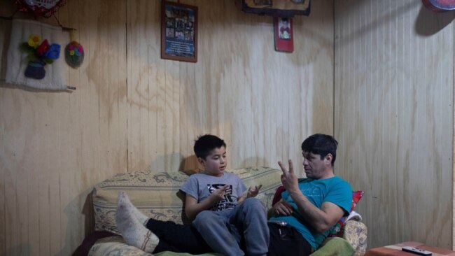 Carlos Guerrero, 40, teaches his son, Diego Guerrero, 7, math in his home in the village of Sotomo, outside the town of Cochamo, Los Lagos, Chile, August 7, 2021. Carlos hopes the window onto the world with the new internet connection will give him more opportunities. (REUTERS/Pablo Sanhueza)