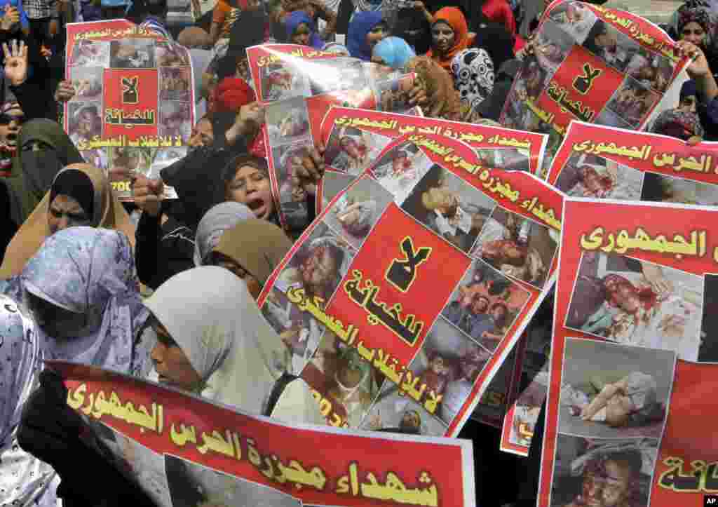Supporters of Egypt's ousted President Mohamed Morsi hold posters showing victims of a military crackdown on their protest camp during a march in Cairo, August 23, 2013.