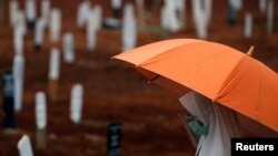 Seorang perempuan mengenakan masker dan pelindung wajah berdoa saat pemakaman seorang kerabat di pemakaman khusus jenazah pasien Covid-19 di TPU Pondok Rangon, Jakarta, 24 September 2020. (Foto: Reuters)