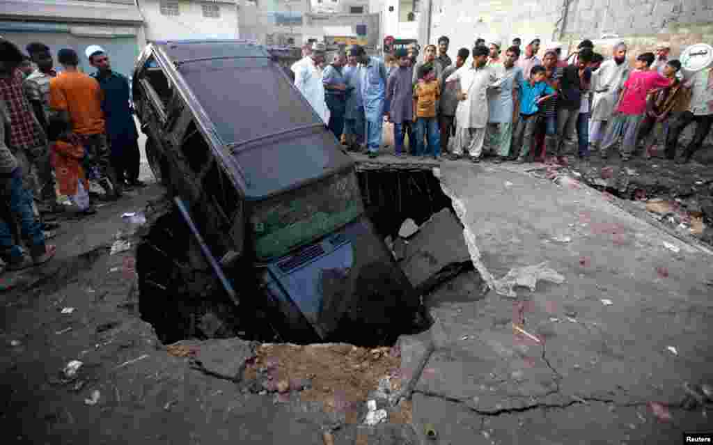 Residents gather at the site of the bomb blast in Karachi, August 7, 2013.