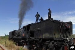 FILE: Workers for the national railways company attend to a steam locomotive after it broke down near Harare Sunday, April, 13, 2014.