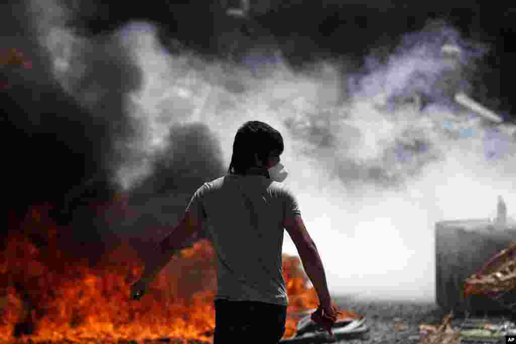 A protester walks in front of a burning barricade during clashes in Taksim Square in Istanbul, June 11, 2013. 