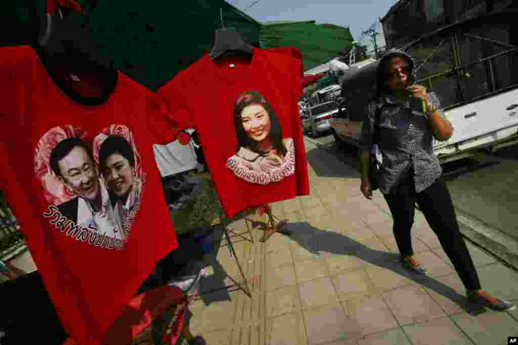 A pro-government supporter passes t-shirts with portraits of Prime Minister Yingluck Shinawatra and her self-exiled brother Thaksin at the gate of the National Anti-Corruption Commission office in Bangkok, Feb. 27, 2014.&nbsp;