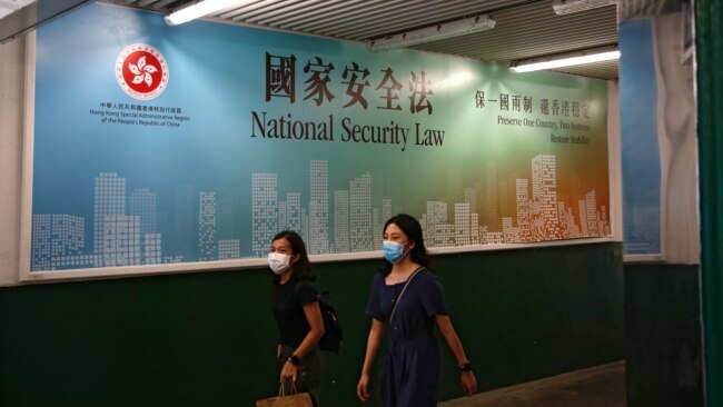 行人走过香港政府在街头张贴的港版国安法宣传标语。(2020年6月29日)