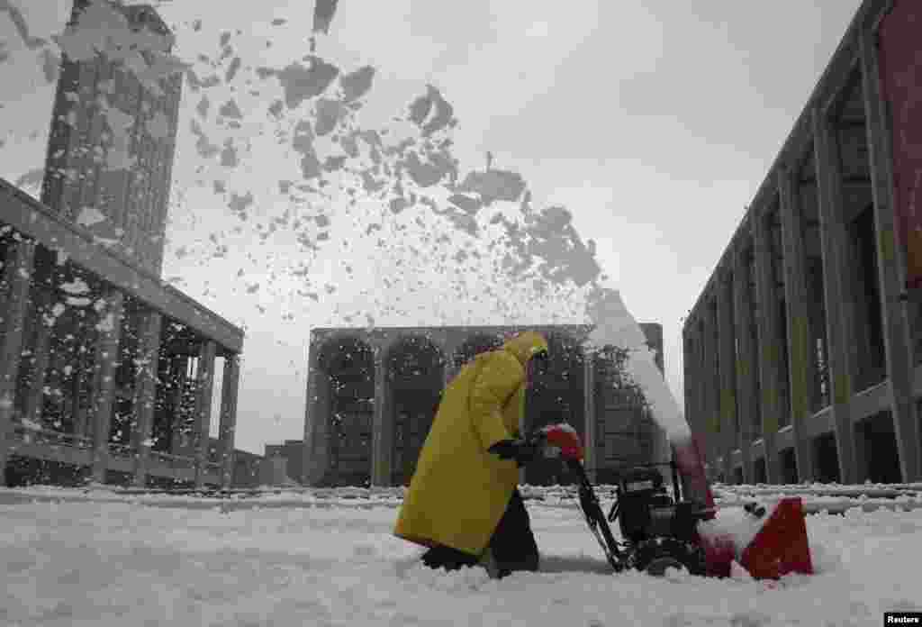 A worker uses a snow blower to clear snow off the steps at Lincoln Center, the site of New York Fashion Week, in the Manhattan borough of New York, Feb. 13, 2014. 