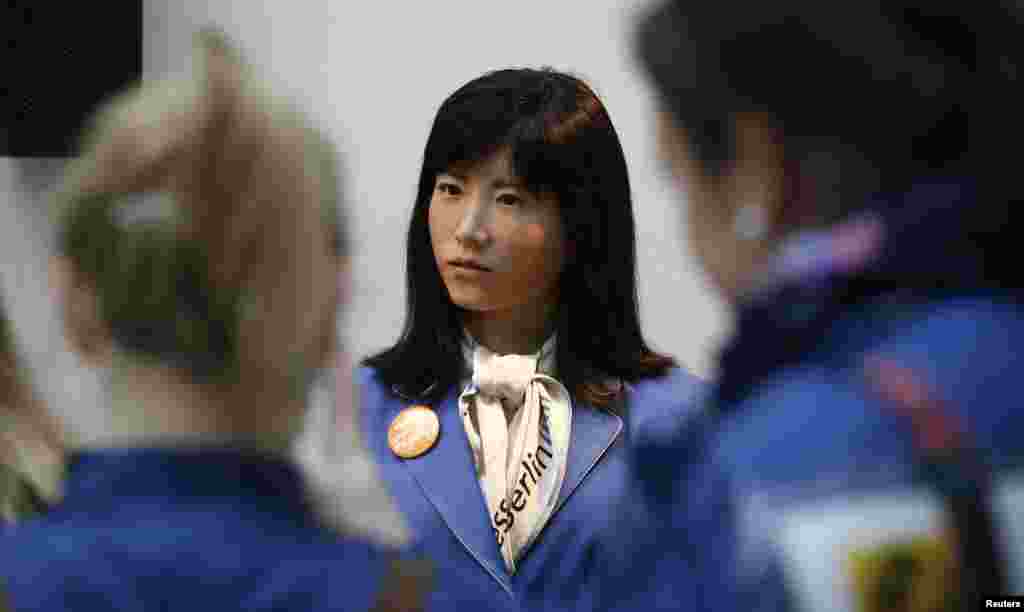 Visitors listen to communication android &#39;Chihira Kanae&#39; (C) at an information counter at the International Tourism Trade Fair (ITB) in Berlin, Germany. &#39;Chihira Kanae&#39;, which was created by Toshiba, has her own information counter where she welcomes visitors and provides information on the trade fair and answers any questions visitors may have in English, German, Japanese and Chinese.