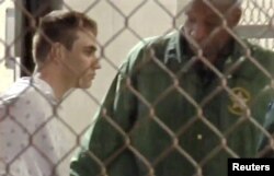 Police escort Nikolas Cruz into Broward County Jail following a shooting incident at Marjory Stoneman Douglas High School, in Fort Lauderdale, Florida, Feb. 15, 2018 in a still image from video.