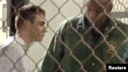 Una imagen tomada de video muestra a la policía acompañando a Nikolas Cruz en la cárcel del condado Broward luego de un tiroteo en la escuela secundaria Marjory Stoneman Douglas en Fort Lauderdale, Florida, el 15 de febrero de 2018.