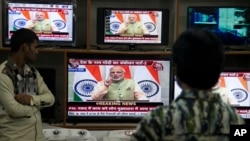 People watch Indian Prime Minister Narendra Modi addressing the nation, on television in Hyderabad, India, Dec. 31, 2016. 