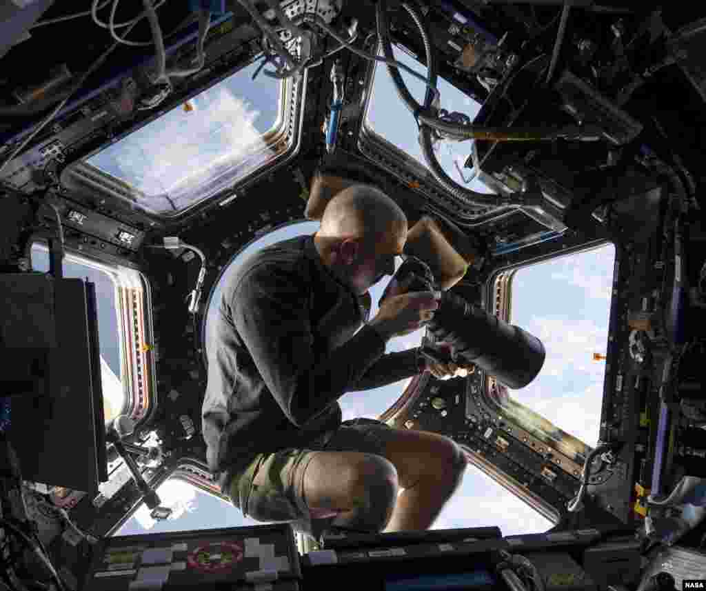 NASA picture inside the Cupola aboard the International Space Station shows NASA astronaut Chris Cassidy, an Expedition 36 flight engineer, using a 400mm lens on a digital still camera to photograph a target of opportunity on Earth some 250 miles below him, June 10, 2013.