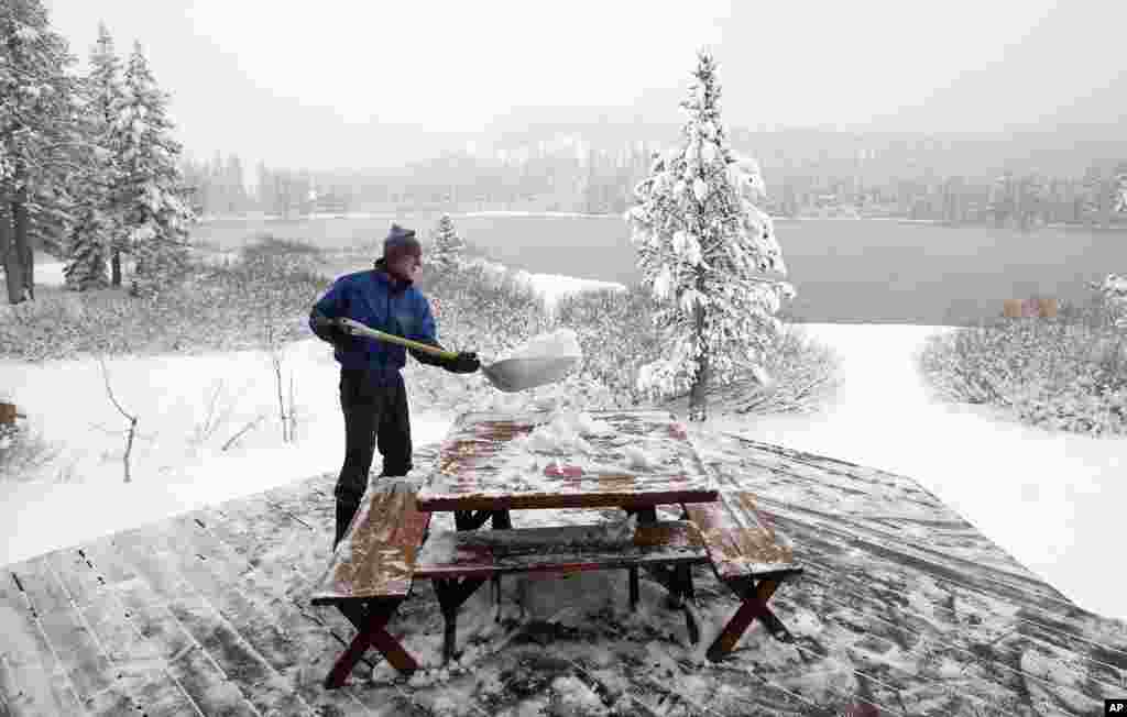 Mickey Gray cleans snow from the deck of his home overlooking Serene Lakes near Soda Springs, California, Oct. 28, 2013. As much as 10 inches of snow fell in the Sierra Nevada near Donner Summit overnight.