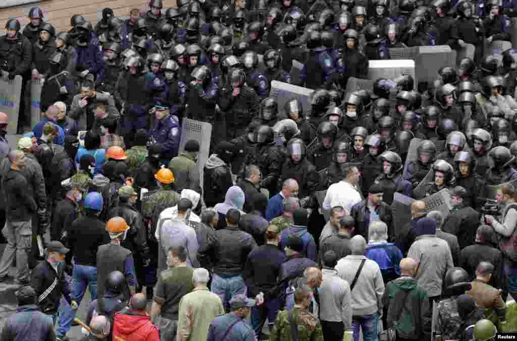 Pro-Russian supporters gather opposite Ukrainian Interior Ministry members standing in formation outside the regional government headquarters in Luhansk, Ukraine, April 29, 2014.