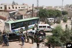 Syrian government buses and a number of the Syrian Arab Red Crescent ambulances at the entrance of Daraya, a suburb of Damascus, Syria, Aug. 26, 2016. Rebels in Daraya agreed to evacuate after four years of grueling bombardment and a crippling siege that has left the sprawling suburb southwest of the capital in ruins.