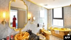 Un membre du personnel pose pour une photographie à l'intérieur de la suite exécutive de deux chambres à coucher de 1000 dollars par nuit du nouvel hôtel Dolce Hanoi Golden Lake, le premier hôtel plaqué or au monde, à Hanoi le 2 juillet 2020.