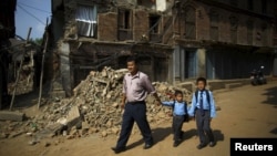 Birendra Karmacharya (L) walks past the debris of collapsed houses while holding the hand of his younger son Saksham Karmacharya, 4, along with his elder son Biyon Karmacharya (R), 9, as they head towards the school in Bhaktapur, Nepal, May 31, 2015. 