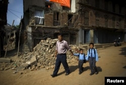 Birendra Karmacharya (L) walks past the debris of collapsed houses while holding the hand of his younger son Saksham Karmacharya, 4, along with his elder son Biyon Karmacharya (R), 9, as they head towards the school in Bhaktapur, Nepal, May 31, 2015.