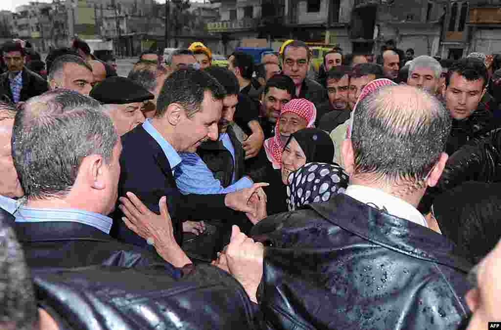 Syria's President Bashar al-Assad (C) smiles as he speaks to local supporters in Baba Amr. (Reuters/SANA)