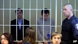 FILE - Two Russian soldiers stand in a cage during a trial hearing in Kiev, Sept. 29, 2015. The two were captured by Ukraine’s forces in mid-May in eastern Ukraine. Russia’s Defense Ministry has said the Russians "were not active servicemen".