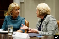 Secretary of Education Betsy DeVos, left, speaks with Commissioner Pam Stewart of the Florida Department of Education before a meeting between President Donald Trump and state and local officials to discuss school safety, in the Roosevelt Room of the White House, Feb. 22, 2018, in Washington.