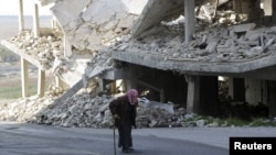 An elderly man walks past a damaged building in the rebel-controlled area of Maaret al-Numan town in Idlib province, Syria, Dec. 21, 2015. 