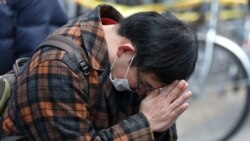 A man prays for victims in front of an office building, where a fire broke out the previous day, in Osaka, Japan, on Dec. 18, 2021.