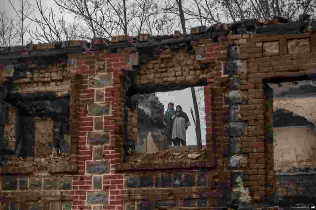 Kashmiri women stand near houses destroyed in a gunbattle on the outskirts of Srinagar, Indian controlled Kashmir.