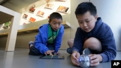 Apple Camp students Brandon Wong, 9, left, and Matthew Choy, 12, learn to program robots using the Sphero SPRK+ with the Lightning Lab application during a Coding Games and Programming Robots session in San Francisco, Wednesday, July 27, 2016. (AP Photo/J