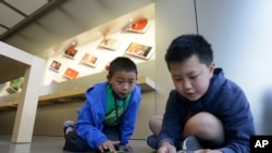 Apple Camp students Brandon Wong, 9, left, and Matthew Choy, 12, learn to program robots using the Sphero SPRK+ with the Lightning Lab application during a Coding Games and Programming Robots session in San Francisco, Wednesday, July 27, 2016. (AP Photo/J