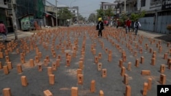反對政變的抗議者走在緬甸曼德勒佈滿磚塊路障的街頭。 (2021年3月10日)