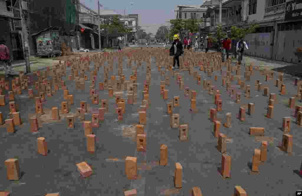 An anti-coup protester walks through a road blocked with bricks in Mandalay, Myanmar.