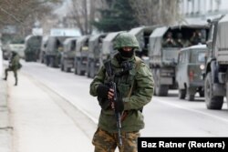 Prajurit bersenjata menunggu di kendaraan tentara Rusia di luar pos penjaga perbatasan Ukraina di Kota Krimea Balaclava. (Foto: REUTERS/Baz Ratner)