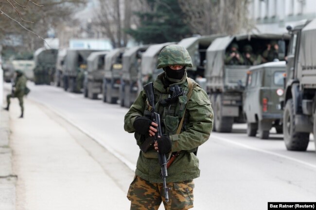 Prajurit bersenjata menunggu di kendaraan tentara Rusia di luar pos penjaga perbatasan Ukraina di Kota Krimea Balaclava. (Foto: REUTERS/Baz Ratner)