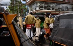 Para pengemudi autorickshaw (semacam becak bermotor) mengenakan masker, mengobrol sambil menunggu pelanggan di Kochi, negara bagian Kerala, India, Kamis, 25 Juni 2020.