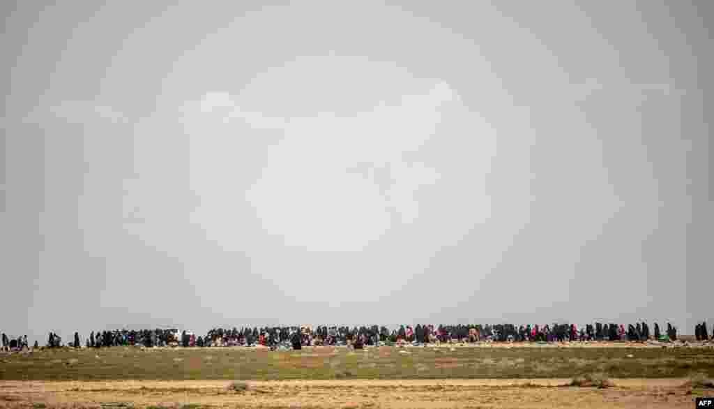 Women and children wait in a field after fleeing Baghouz in Syria&#39;s northern Deir Ezzor province, the last area under Islamic State group control.