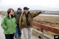 FILE - Local resident Fran Karr, right, with her husband Jason Karr, center, points out to Democratic presidential candidate Sen. Amy Klobuchar the location of their flooded home, of Pacific Junction, Iowa, Friday, March 29, 2019.