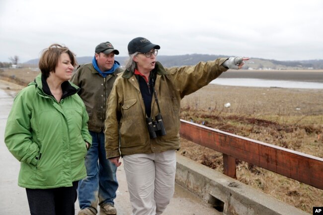 FILE - Local resident Fran Karr, right, with her husband Jason Karr, center, points out to Democratic presidential candidate Sen. Amy Klobuchar the location of their flooded home, of Pacific Junction, Iowa, Friday, March 29, 2019.