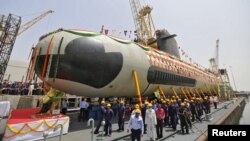 Employees stand near the Indian Navy's first Scorpene submarine before being undocked on April 6 at a naval vessel ship building yard in Mumbai.