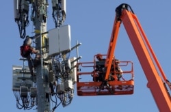 FILE - Workers install Verizon's 5G telecommunications equipment on a tower in Orem, Utah, U.S. December 3, 2019. (REUTERS/George Frey)